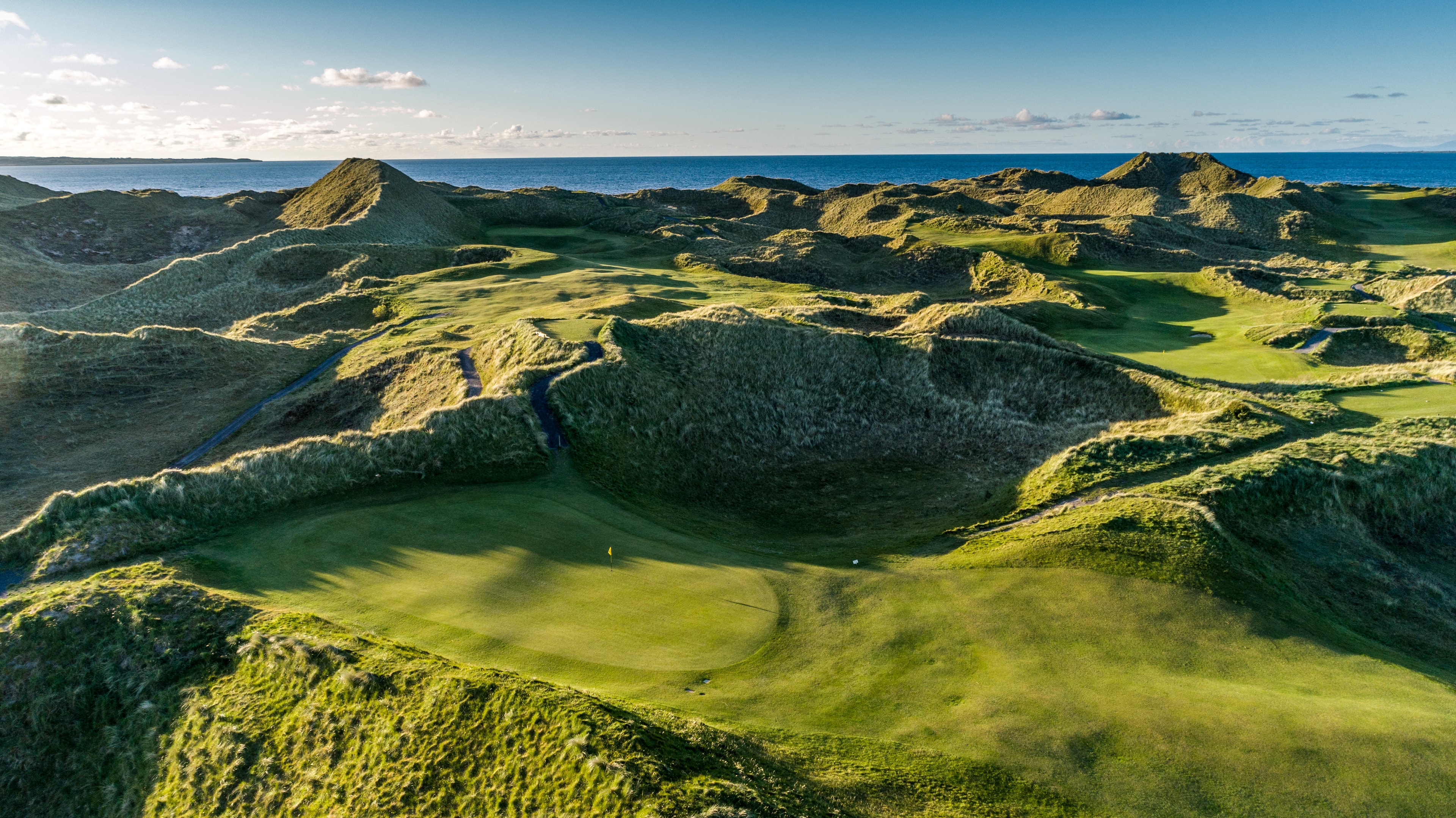 A green nestled deep in the dunes at Enniscrone Golf Club with the Atlantic beyond