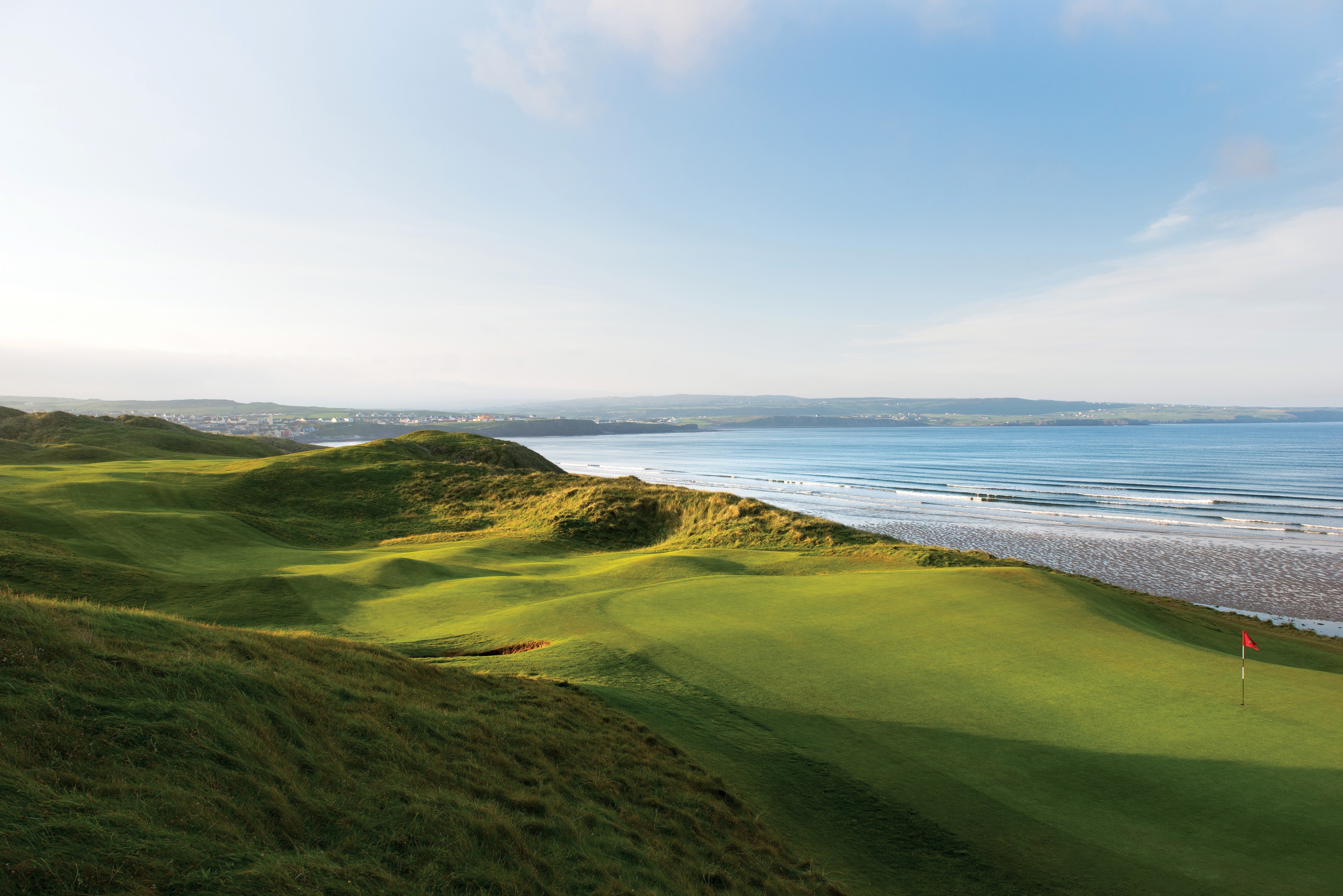 7th green at Lahinch Golf Club with Atlantic waves breaking on the shore